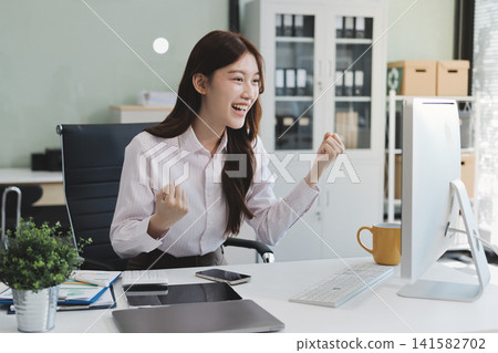 Young businesswoman professional employee using pc doing online banking analysing at workplace. Asian middle-aged business woman working on laptop computer in office, taking notes. Banner, copy space 141582702