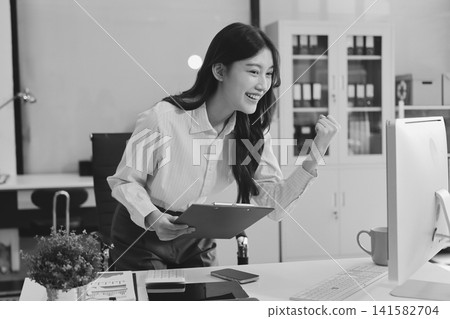 Young businesswoman professional employee using pc doing online banking analysing at workplace. Asian middle-aged business woman working on laptop computer in office, taking notes. Banner, copy space Young businesswoman professional employee using pc doing online banking analysing at workplace. Asian middle-aged business woman working on laptop computer in office, taking notes. Banner, copy space 141582704