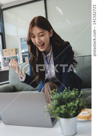 Asian businesswoman sitting at work using laptop talking and consulting in office Asian businesswoman sitting at work using laptop talking and consulting in office 141582725