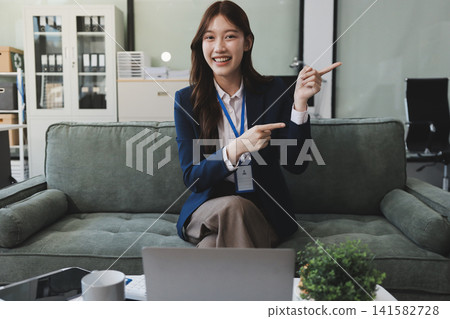 Asian businesswoman sitting at work using laptop talking and consulting in office Asian businesswoman sitting at work using laptop talking and consulting in office 141582728