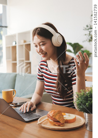 Asian woman using computer remote for business studying, watching online virtual webinar training meeting, video call. asian business woman talking on laptop in home office. Banner, copy space Asian woman using computer remote for business studying, watching online virtual webinar training meeting, video call. asian business woman talking on laptop in home office. Banner, copy space 141582739