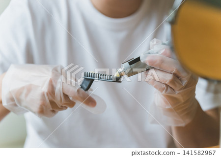 一名男子正在用乳霜狀染髮劑為自己的灰髮染髮。 一名男子正在用乳霜狀染髮劑為自己的灰髮染髮。 141582967