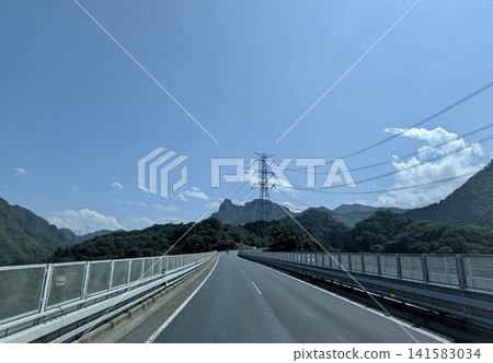 Highways and power transmission towers running through mountainous areas under a clear blue sky Highways and power transmission towers running through mountainous areas under a clear blue sky 141583034