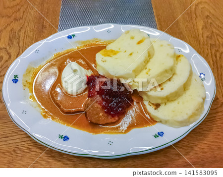 Traditional Czech svickova beef sirloin with bread dumplings, cranberry sauce and cream on white plate Traditional Czech svickova beef sirloin with bread dumplings, cranberry sauce and cream on white plate 141583095