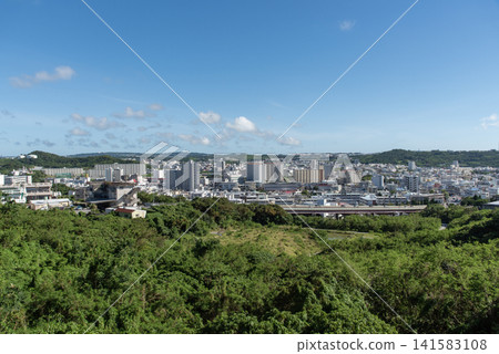 從山頂可以眺望到湛藍的天空、前景的綠樹和遠處的城鎮景色。 從山頂可以眺望到湛藍的天空、前景的綠樹和遠處的城鎮景色。 141583108