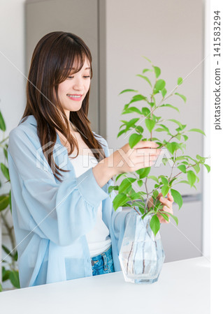 Flower vase, young woman putting plants in a vase Flower vase, young woman putting plants in a vase 141583294