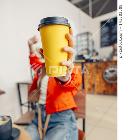 woman holding yellow takeaway coffee cup toward camera in cafe selective focus close up of hand with disposable cup modern lifestyle concept of coffee to go and urban daily routine woman holding yellow takeaway coffee cup toward camera in cafe selective focus close up of hand with disposable cup modern lifestyle concept of coffee to go and urban daily routine 141583389