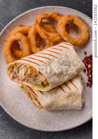 Grilled chicken shawarma or doner with tomatoes, cucumber, and sauces, takeout food Grilled chicken shawarma or doner with tomatoes, cucumber, and sauces, takeout food 141583562
