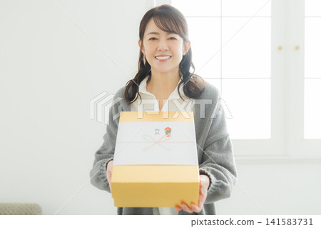 一位女士遞上一份用精美包裝紙包裹的禮物。 141583731