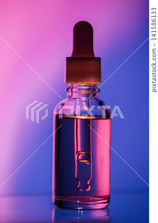 Glass dropper bottle filled with colorful liquid against a gradient background of purple and blue hues, showcasing the product's clarity and design Glass dropper bottle filled with colorful liquid against a gradient background of purple and blue hues, showcasing the product's clarity and design 141586133