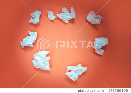 Crumpled white paper balls arranged in a circular pattern on a vibrant orange background, showcasing creative waste and artistic expression in minimalistic design Crumpled white paper balls arranged in a circular pattern on a vibrant orange background, showcasing creative waste and artistic expression in minimalistic design 141586196