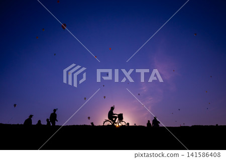 Early morning gradient, hot air balloon, and silhouette of a cyclist. Early morning gradient, hot air balloon, and silhouette of a cyclist. 141586408