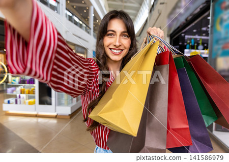 Smiling young woman with many color paper shopping bags in hand Smiling young woman with many color paper shopping bags in hand 141586979