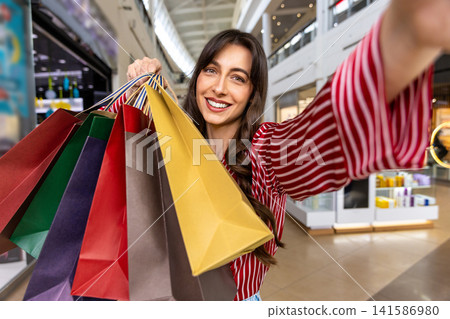 Smiling young woman with many color paper shopping bags in hand Smiling young woman with many color paper shopping bags in hand 141586980