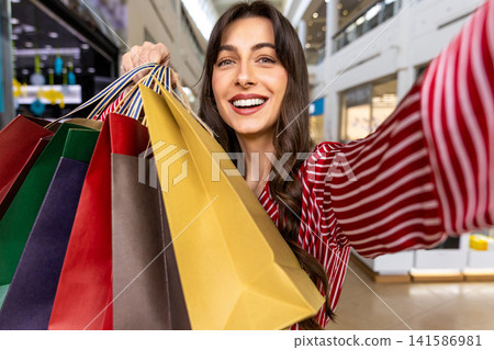 Smiling young woman with many color paper shopping bags in hand Smiling young woman with many color paper shopping bags in hand 141586981