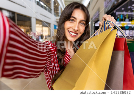 Smiling young woman with many color paper shopping bags in hand Smiling young woman with many color paper shopping bags in hand 141586982