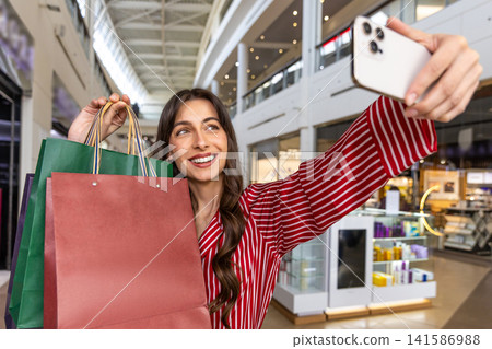 Pretty young woman making selfie in a shopping mall Pretty young woman making selfie in a shopping mall 141586988
