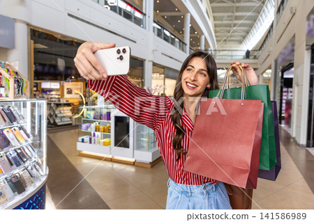 Pretty young woman making selfie in a shopping mall Pretty young woman making selfie in a shopping mall 141586989
