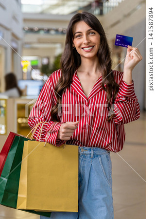 Smiling young woman holding a credit card in hands Smiling young woman holding a credit card in hands 141587894
