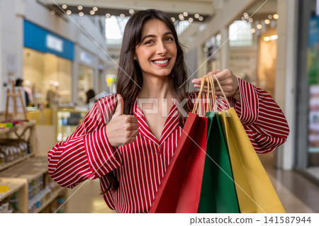 Young woman in a red shirt feeling happy and excited after shopping Young woman in a red shirt feeling happy and excited after shopping 141587944