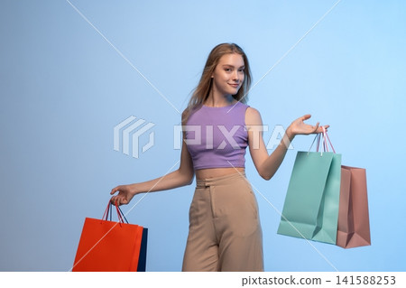 Young woman confidently balancing colorful shopping bags after successful retail therapy and consumer spending Young woman confidently balancing colorful shopping bags after successful retail therapy and consumer spending 141588253