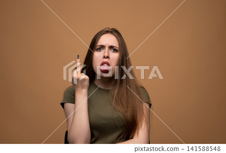Young woman showing middle finger gesture and sticking out tongue, expressing anger and defiant rude emotion Young woman showing middle finger gesture and sticking out tongue, expressing anger and defiant rude emotion 141588548