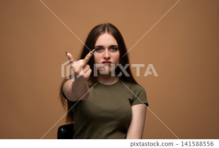 Young woman showing middle finger gesture with angry expression, conveying defiance and frustration Young woman showing middle finger gesture with angry expression, conveying defiance and frustration 141588556