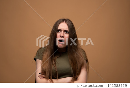 Young woman reacting with a shocked expression, jaw dropped and eyes wide open. Capturing surprise and disbelief emotions Young woman reacting with a shocked expression, jaw dropped and eyes wide open. Capturing surprise and disbelief emotions 141588559