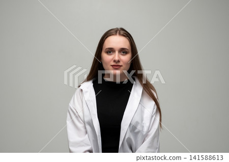 Young woman with brown hair wearing a white shirt and black top, standing confidently looking at the camera Young woman with brown hair wearing a white shirt and black top, standing confidently looking at the camera 141588613