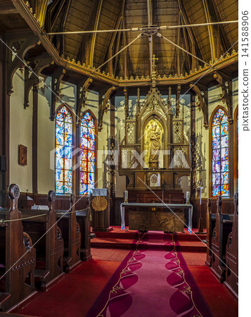 Historic Church Interior With Ornate Altar, Stained Glass Windows and Wooden Pews in Warm Light Historic Church Interior With Ornate Altar, Stained Glass Windows and Wooden Pews in Warm Light 141588906