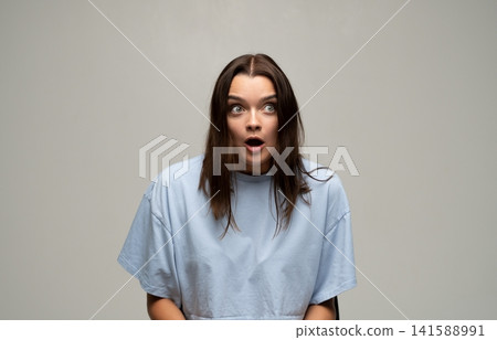 Young woman with wide-eyed surprise, expressing shock and disbelief, mouth open reacting to unexpected news Young woman with wide-eyed surprise, expressing shock and disbelief, mouth open reacting to unexpected news 141588991