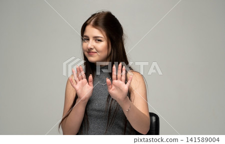 Young woman showing stop gesture, refusing and denying something with palms outward, expressing disapproval 141589004