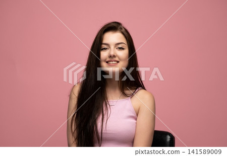 Young brunette woman smiling broadly, expressing happiness and cheerfulness, looking at camera on pink background Young brunette woman smiling broadly, expressing happiness and cheerfulness, looking at camera on pink background 141589009