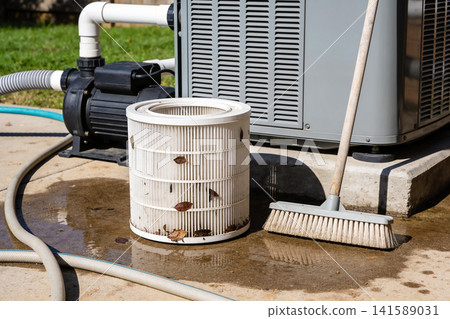 Dirty pool filter and pump with broom on wet concrete during maintenance Dirty pool filter and pump with broom on wet concrete during maintenance 141589031