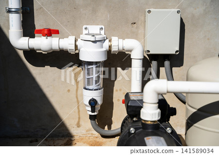 Water filtration system with pump and pressure tank on concrete wall 141589034