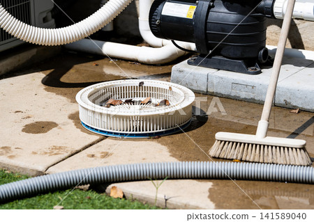 Pool pump basket and debris filter basket with broom and hose on concrete Pool pump basket and debris filter basket with broom and hose on concrete 141589040