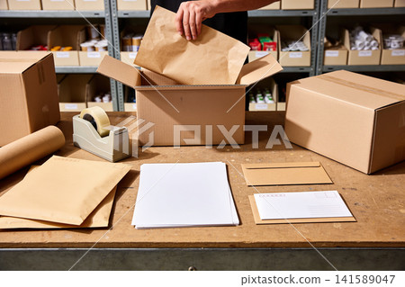 Preparing packages for shipping with boxes, envelopes, and tape on a wooden table Preparing packages for shipping with boxes, envelopes, and tape on a wooden table 141589047