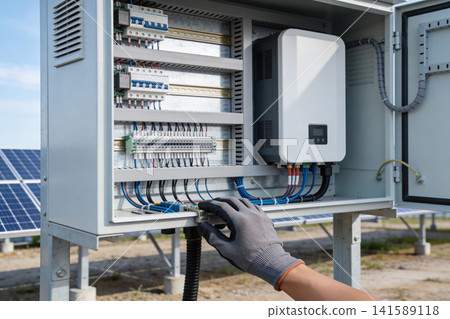 Solar power system inverter and electrical panel with technician's hand 141589118