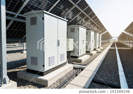 Row of electrical cabinets beneath solar panels at a power generation facility 141589146