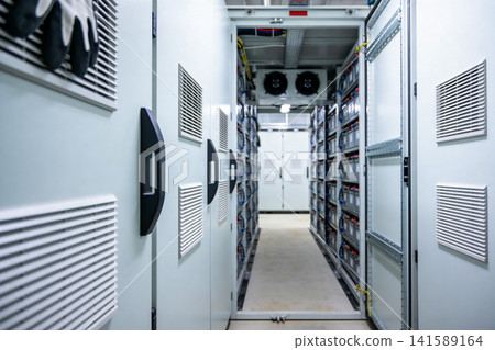 Inside a modern data center with rows of battery storage units and cooling fans Inside a modern data center with rows of battery storage units and cooling fans 141589164