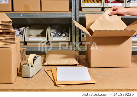 Preparing packages for shipping in a warehouse with organized shelves and supplies Preparing packages for shipping in a warehouse with organized shelves and supplies 141589220