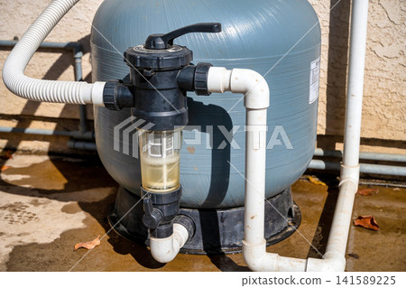 Close-up of a pool filter system with clear debris basket and PVC piping Close-up of a pool filter system with clear debris basket and PVC piping 141589225
