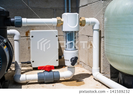 Close-up of pool pump and filtration system plumbing with clear filter housing Close-up of pool pump and filtration system plumbing with clear filter housing 141589232