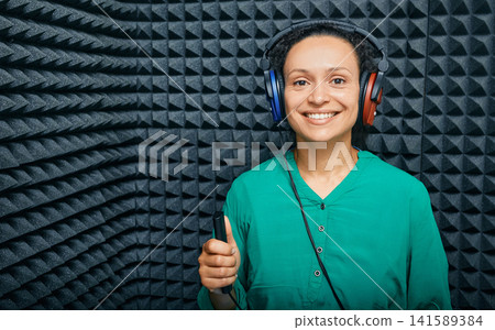 Portrait adult woman while hearing check-up at soundproof audiometric cabin using audiometry headphones and audiometer Portrait adult woman while hearing check-up at soundproof audiometric cabin using audiometry headphones and audiometer 141589384