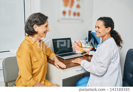 Consultation with experienced female audiologist to mature woman patient at medical clinic. Treatment of hearing loss in senior people Consultation with experienced female audiologist to mature woman patient at medical clinic. Treatment of hearing loss in senior people 141589385