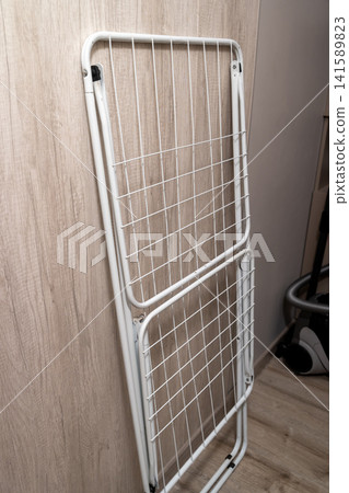 Metal drying rack leaned against a wall inside a room 141589823