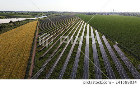Solar panel farm generating clean renewable energy in rural landscape with agricultural fields from aerial perspective Solar panel farm generating clean renewable energy in rural landscape with agricultural fields from aerial perspective 141589834