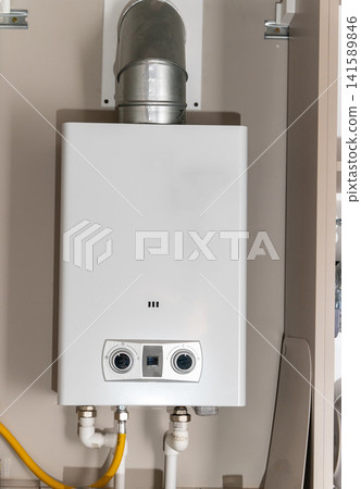 Tankless water heater installed on a wall in a home kitchen Tankless water heater installed on a wall in a home kitchen 141589846