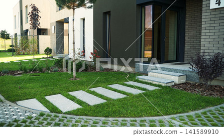 Modern residential architecture featuring townhouses and a green lawn with stepping stones leading to an entrance Modern residential architecture featuring townhouses and a green lawn with stepping stones leading to an entrance 141589910