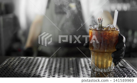 Bartender serving smoking cocktail with dry ice, chilling alcohol drink at a bar counter, preparing refreshing beverage Bartender serving smoking cocktail with dry ice, chilling alcohol drink at a bar counter, preparing refreshing beverage 141589969